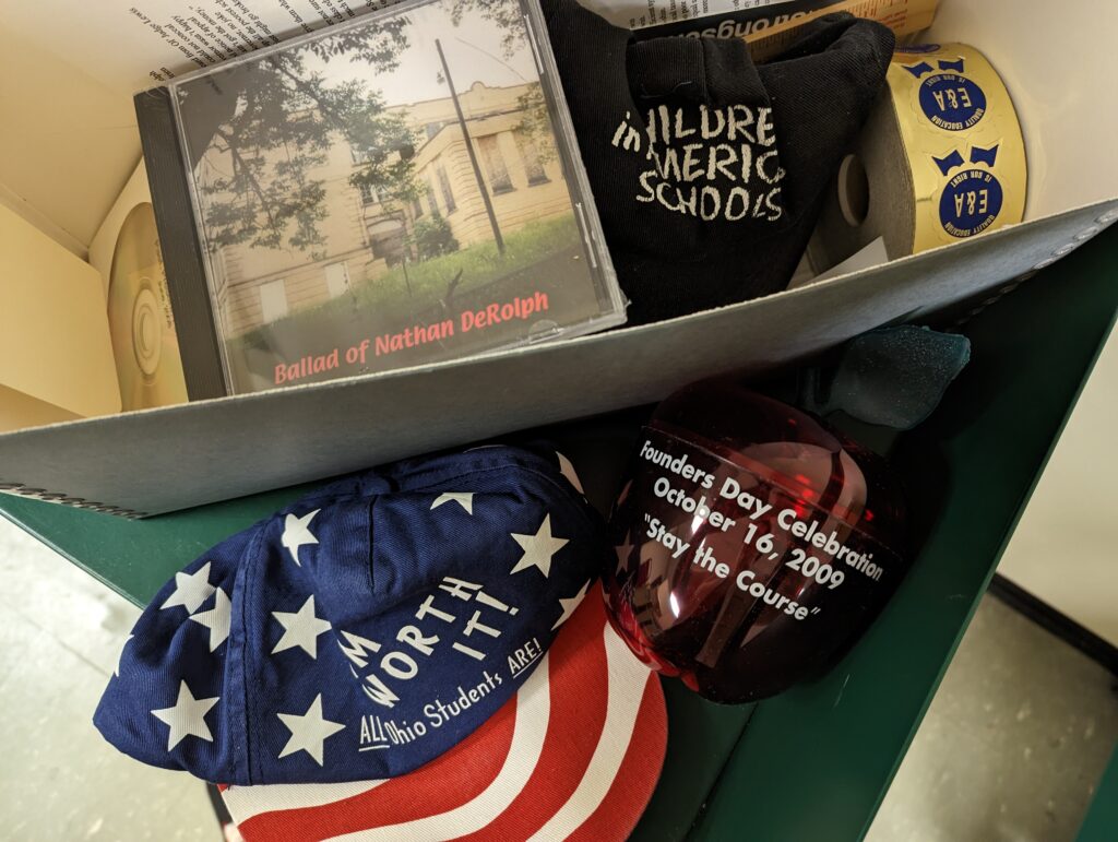 CDs, hats, a plastic apple, and other promotional material are photographed from above