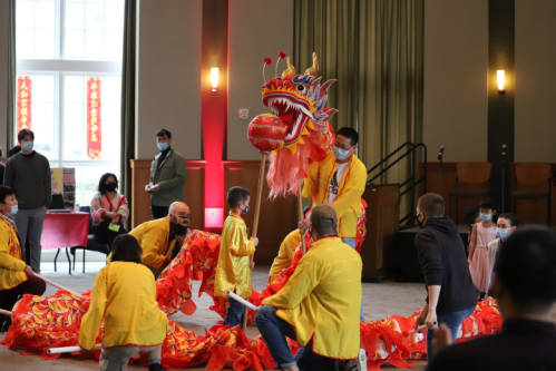 People in yellow shirts preparing a dragon puppet for the dragon dance at a Lunar New Year celebration