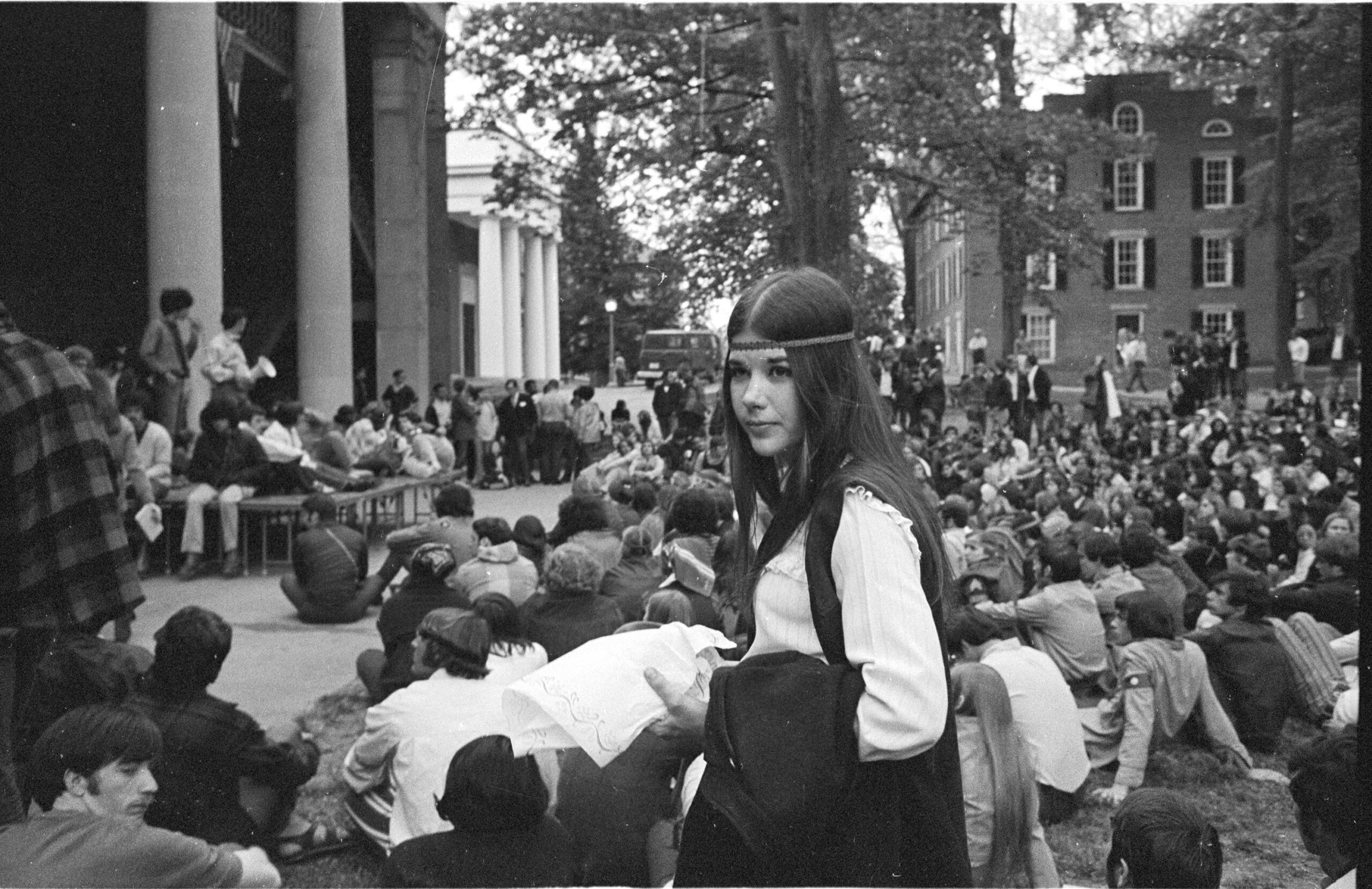 Young woman standing among a seated crowd at a rally on the College Green