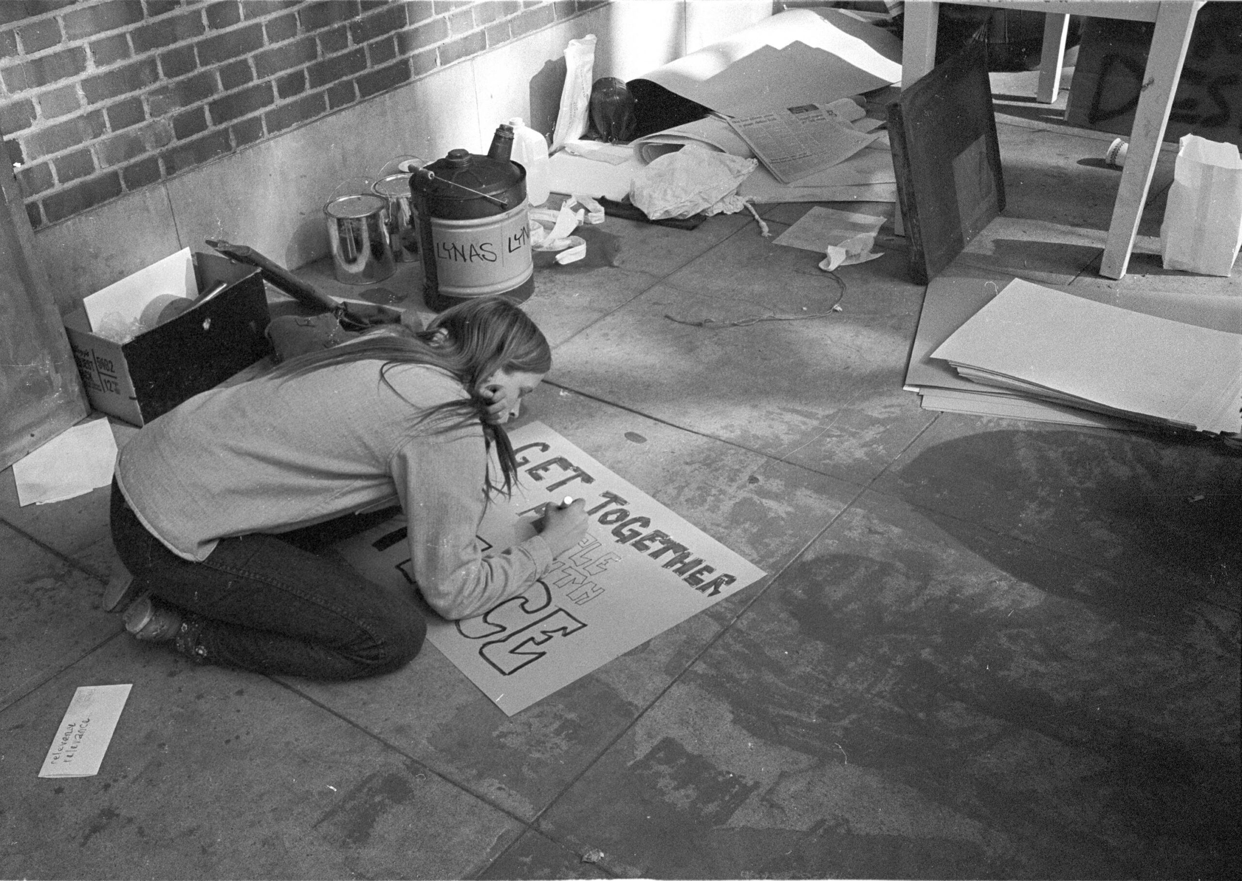Student at rally creating a sign to promote peace