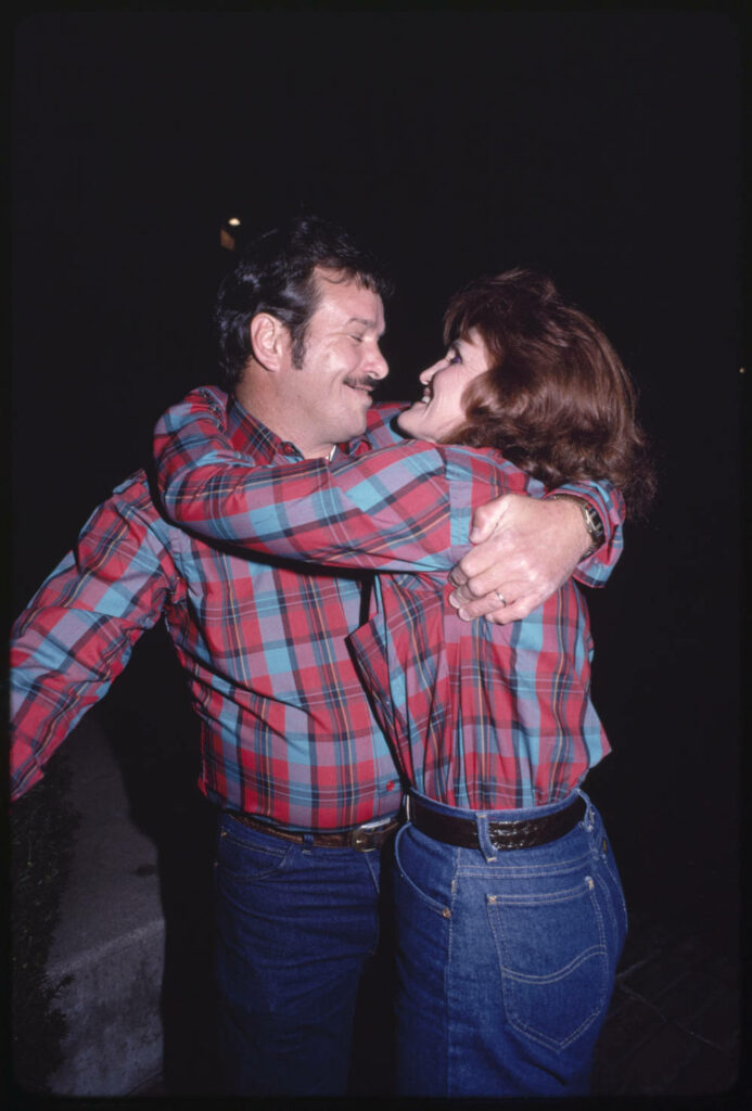 Couple wearing identical plaid shirts while smiling and embracing