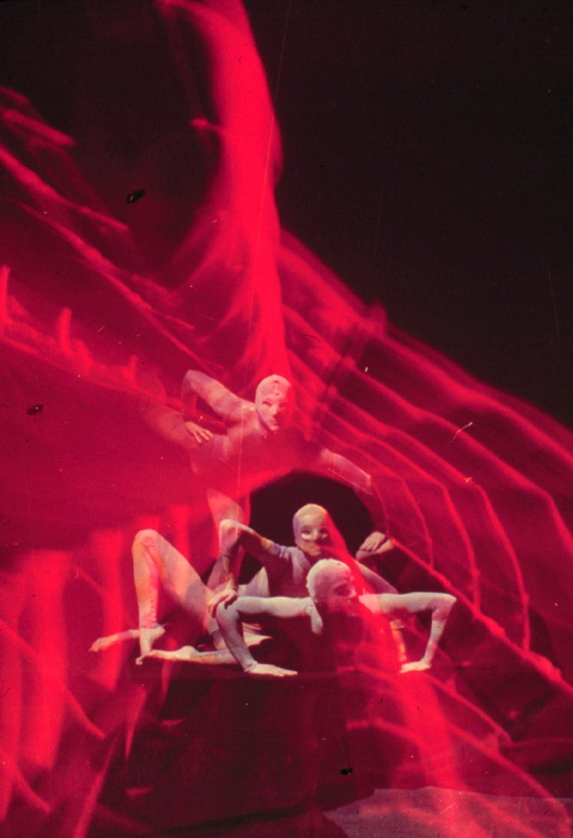 Three dancers illuminated in red light during a performance of "Tribe", created by Alwin Nikolais