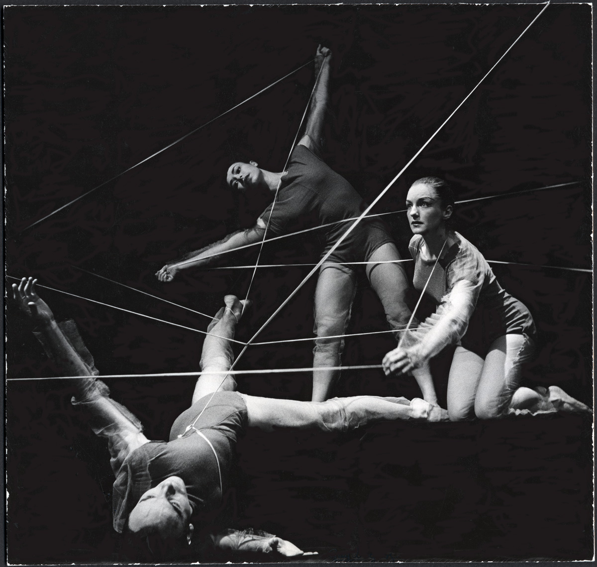 Three dancers with string during a performance of "Village of Whispers", created by Alwin Nikolais
