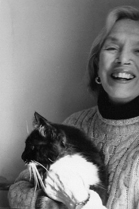 Black and white portrait of Alice Adams laughing with a black and white cat in her arms