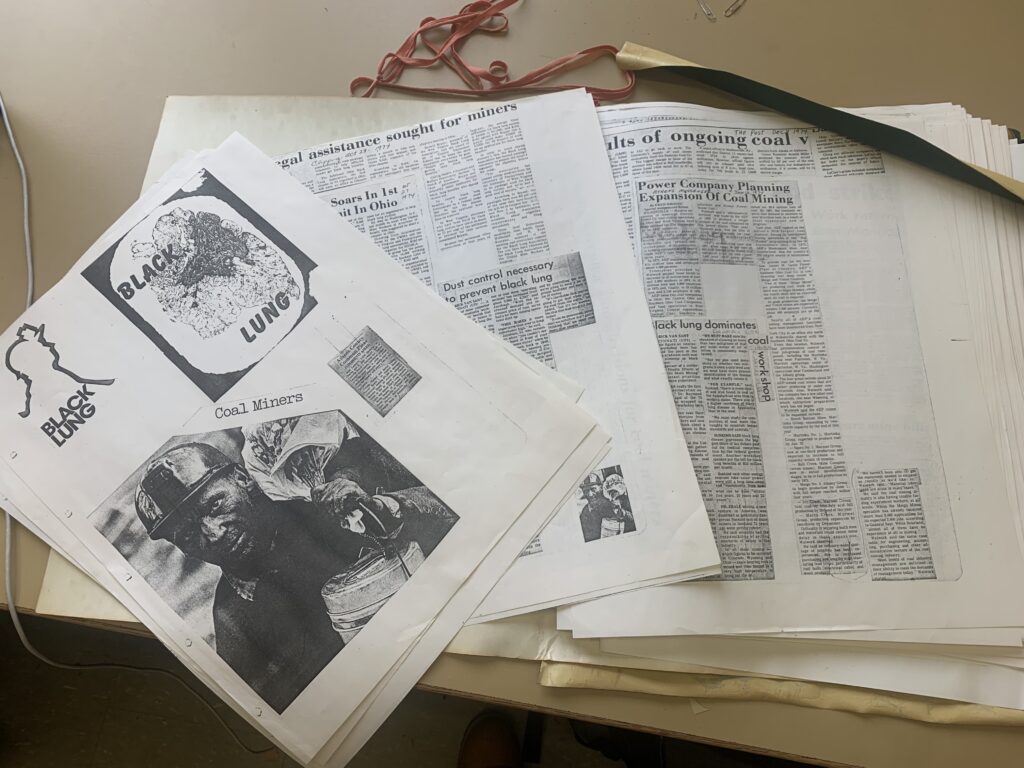 Photocopied newspaper clippings in a scrapbook laying on a table.