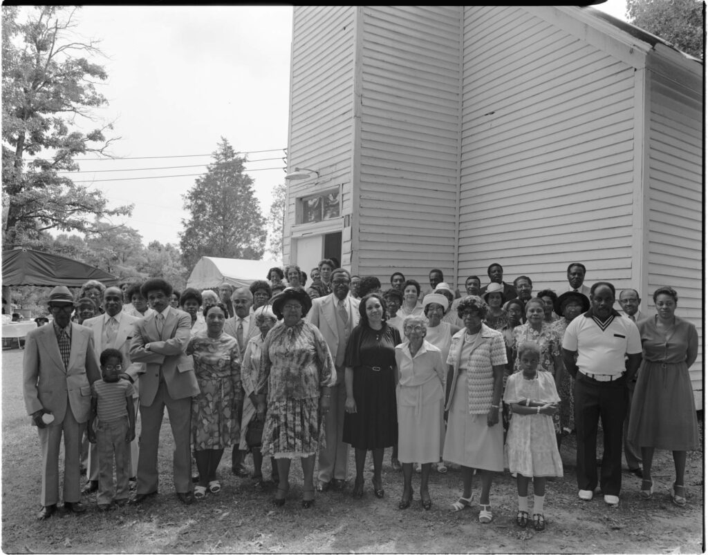 Group portrait of all-Black congregation gathered outside historical Macedonia Missionary Baptist Church in Burlington, Ohio, July 8, 1979