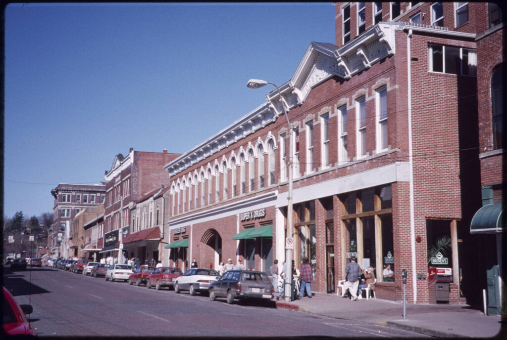 View of brick buildings, people on sidewalk, and cars parked along Court Street, uptown Athens, Ohio, 1996