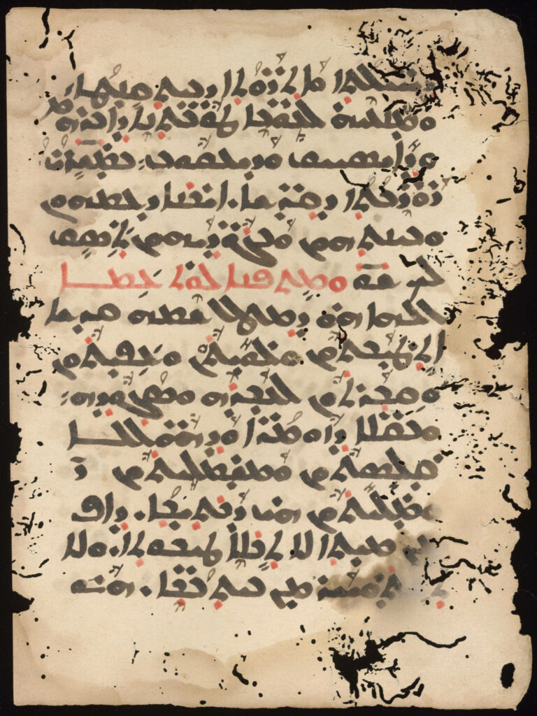 Handwritten manuscript page with Syriac text in black and red ink on paper that has many holes created by insects