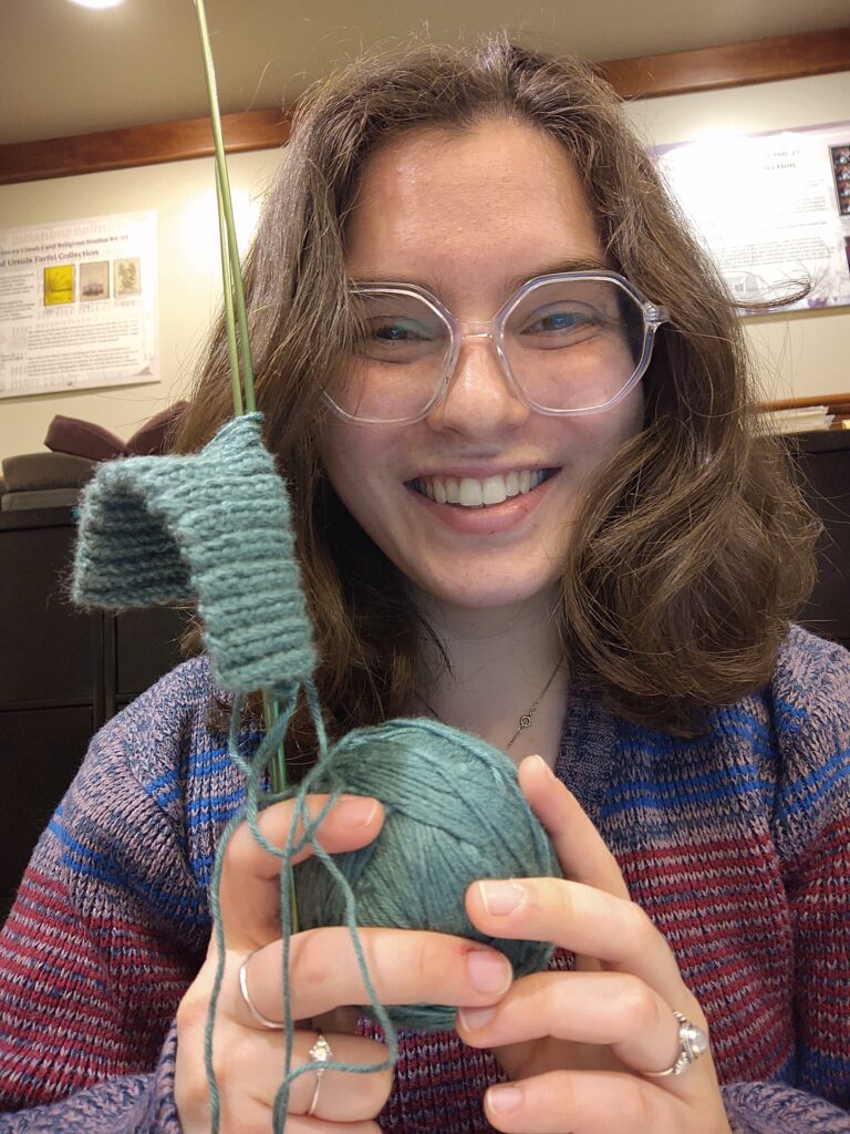 Jessica holding green yarn and knitting needles