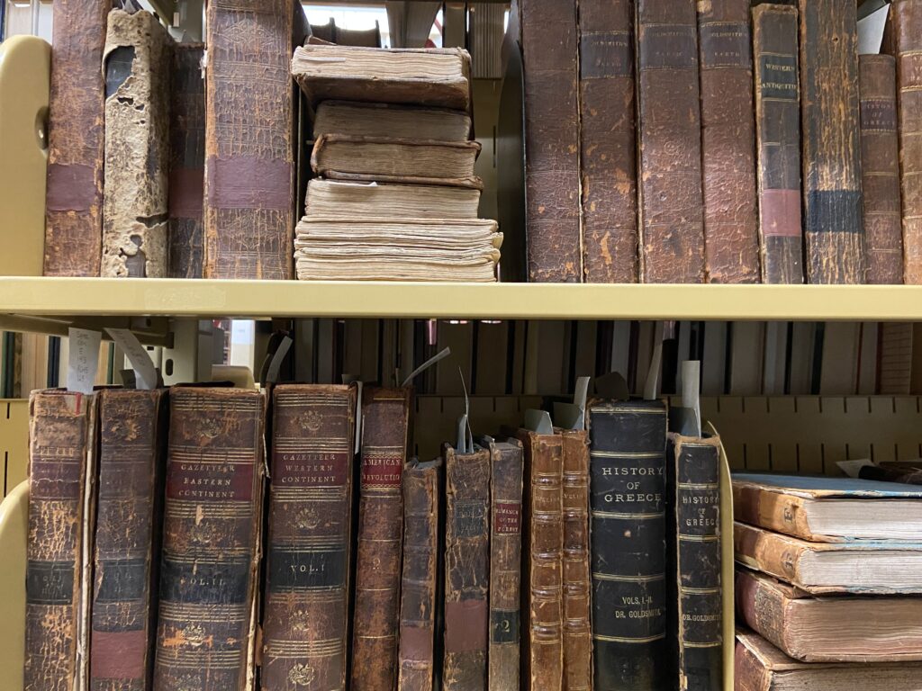 View of older/more fragile books on the shelf in the rare book collection showing some of the wear-and-tear on or along the spine.  