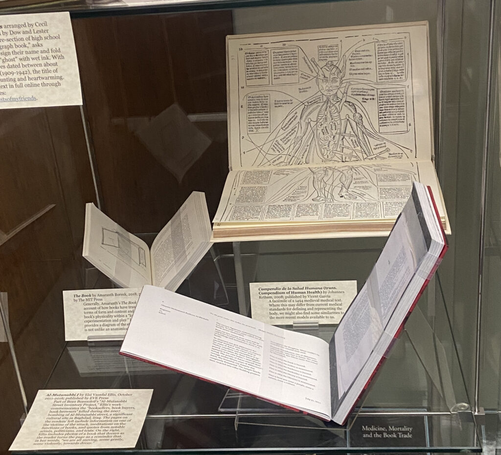 Display middle shelf (from left to right): The Book (back), Compendio de la Salud Humana (back), Al Mutanabbi I (front). 