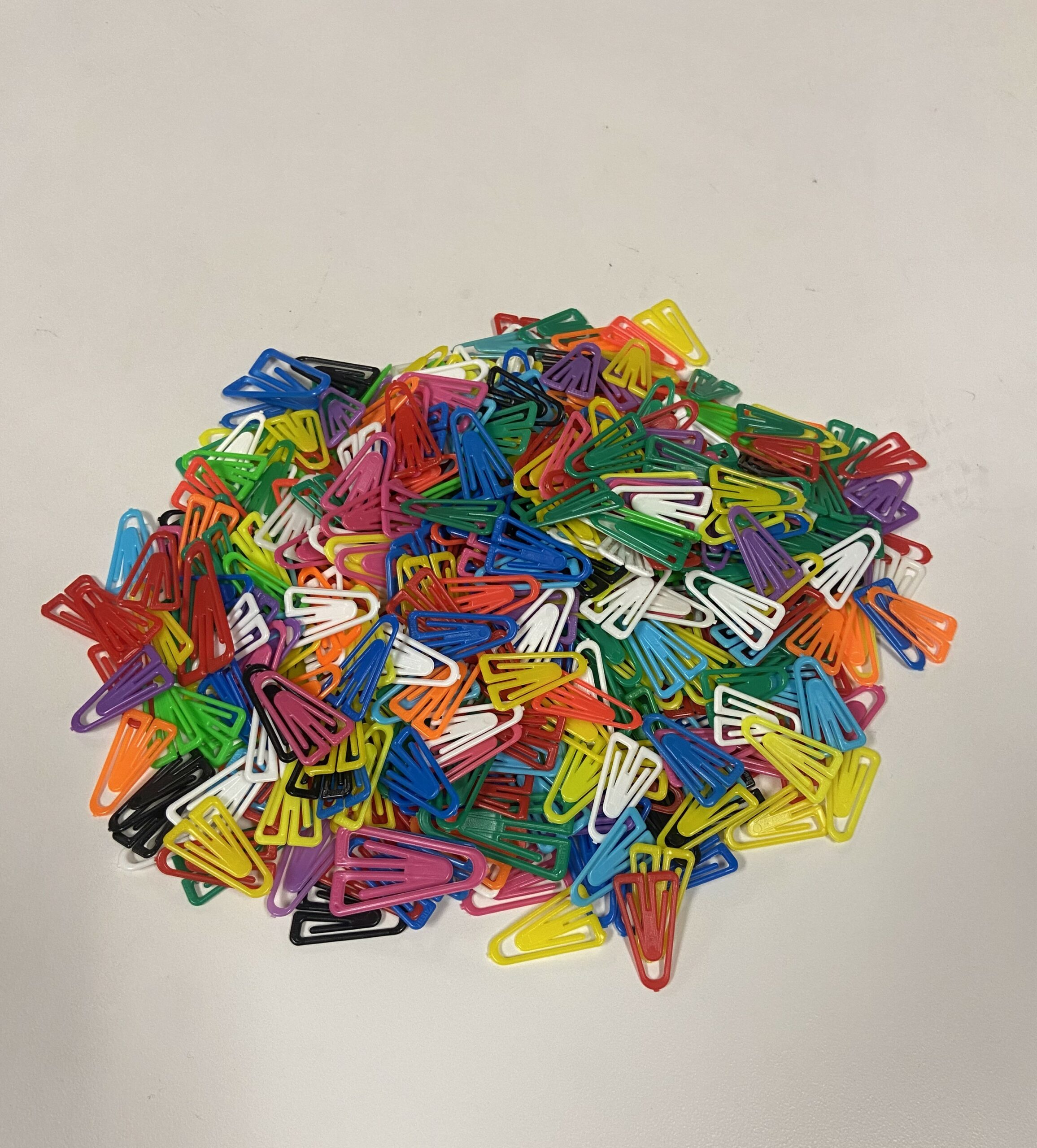 a small pile of colorful paperclips on a white background