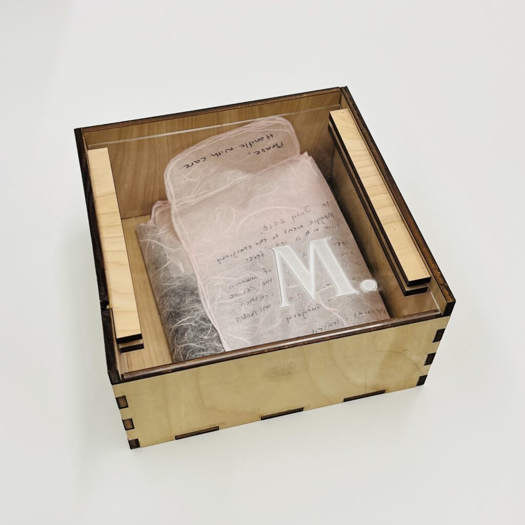 M. by Maggie & Hattie Phillips.Created in 2019 for Letterpress & Bookbinding with instructor Don Adleta. Multi-directional folded pink Thai Unryu (Mulberry) paper with digital and screen-printed images. Contained in a laser-cut and laser-printed wooden box with clear acrylic lid.
