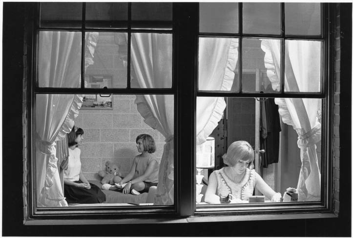 Photo of three women in their dorm room, chatting and reading, 1960s.