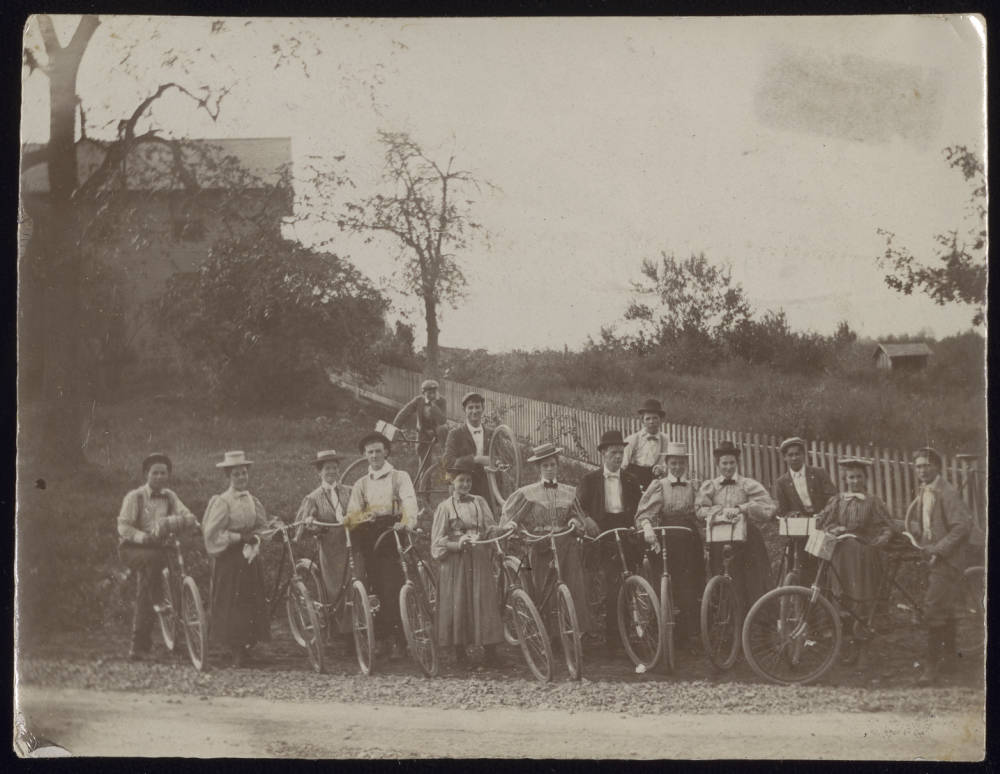 Group portrait of men and women with bikes, circa 1897
