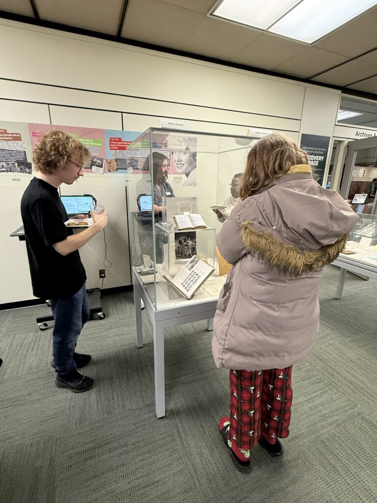 Visitors viewing Grace's diary (center of the case on the pedestal) during the Showcase.