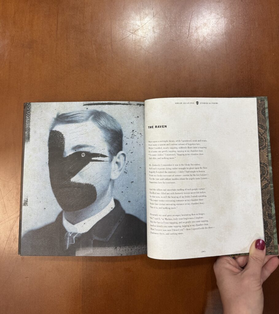 A book is held open to a page with a man’s portrait on the left page overlaid with an illustration of a black bird. On the right page the text of the poem “The Raven” is displayed.  