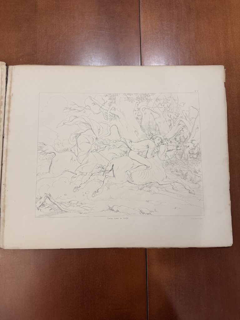 A book lies on open on a brown table to an illustration of two figures on horses.  